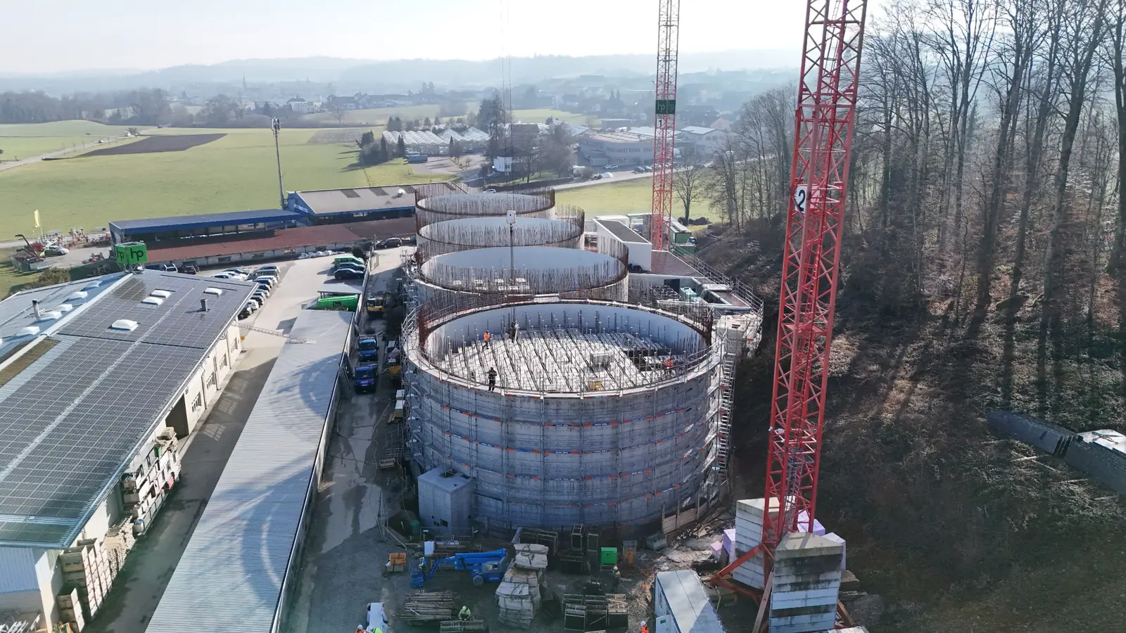 Drohnenaufnahme einer Baustelle mit runden Betonbauten und Baukränen